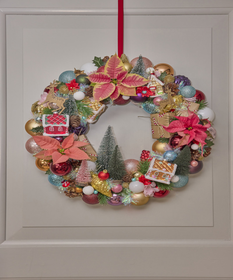 Kolorowy świąteczny wieniec z ciętymi poinsecjami, bombkami, domkami i dekoracjami w stylu retro