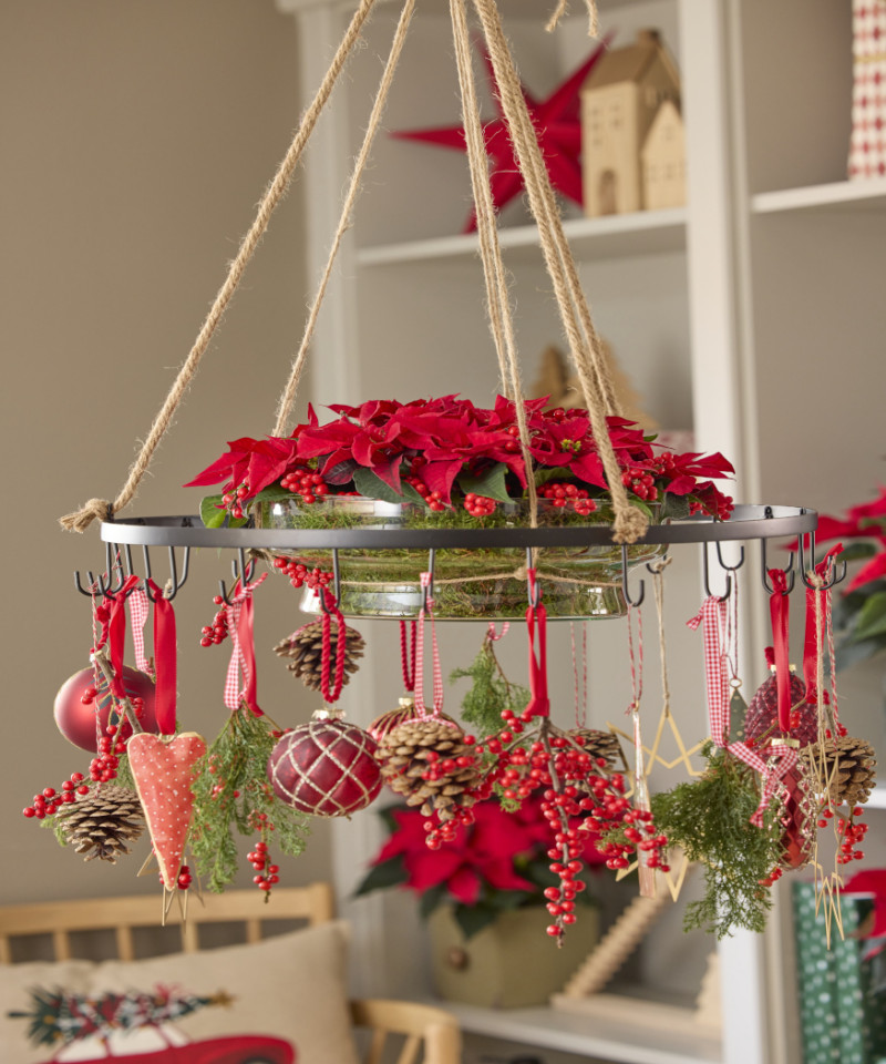 Wisząca dekoracja świąteczna z czerwonymi poinsecjami, szyszkami i ozdobami zawieszonymi na czerwonych wstążkach