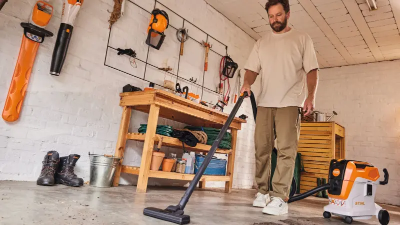 Mężczyzna sprząta podłogę w warsztacie za pomocą akumulatorowego odkurzacza STIHL SEA 60L.