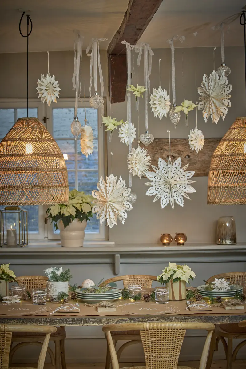 Świąteczna aranżacja stołu w stylu skandynawskim z kremowymi poinsecjami, papierowymi gwiazdami i dekoracjami z naturalnych materiałów.