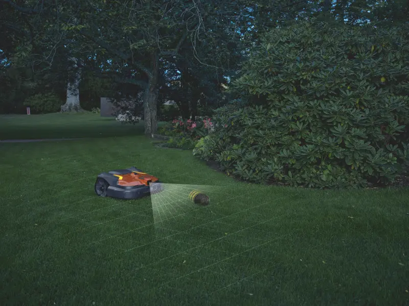Robot koszący Husqvarna z AI Vision pracujący nocą na trawniku, wykrywający przeszkodę - jeża