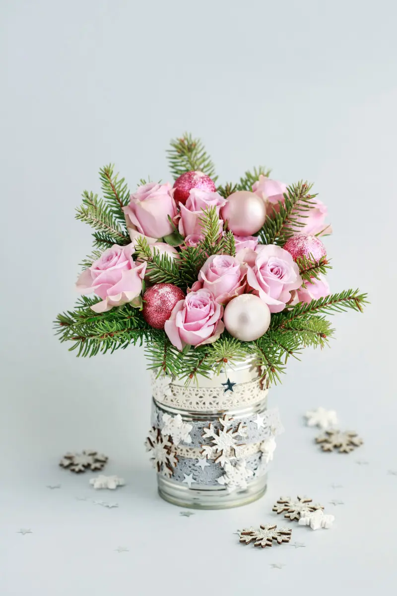 Gotowy świąteczny stroik z puszki – różowe róże, gałązki świerku i bombki w metalowym wazonie jako dekoracja stołu