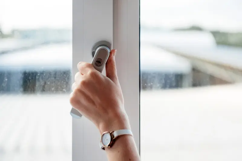 Dłoń otwierająca okno zimą – prawidłowe wietrzenie pomieszczeń