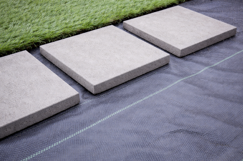 Układanie płyt w trawie na geowłókninie, betonowe płyty na tkaninie pod ścieżkę ogrodową.